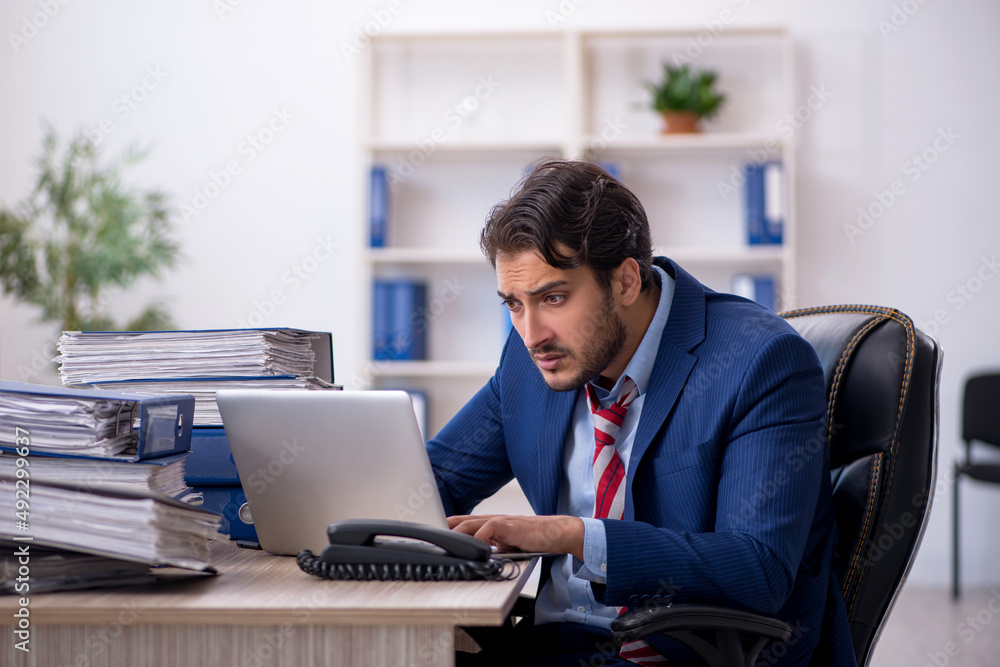 Young male employee and too much work in the office Young male employee and too much work in the office