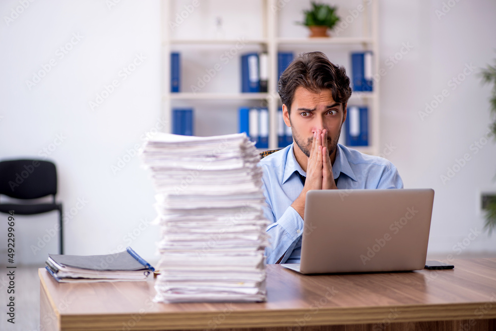 Young male employee and too much work in the office Young male employee and too much work in the office
