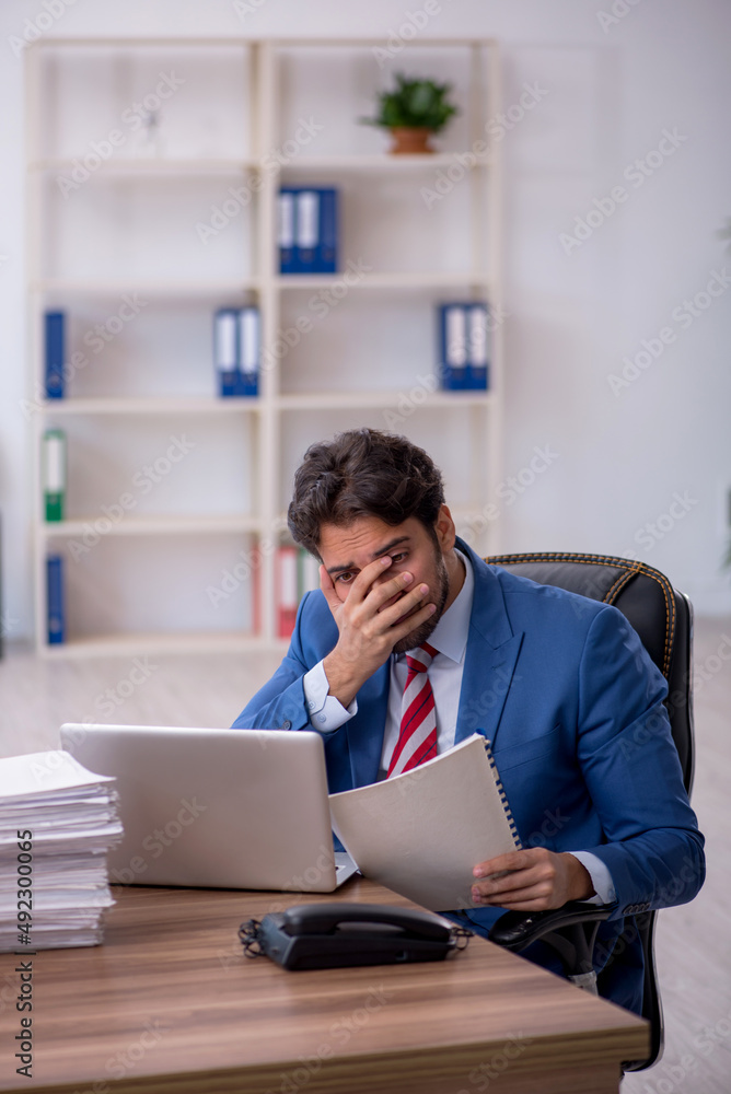 Young male employee and too much work in the office Young male employee and too much work in the office