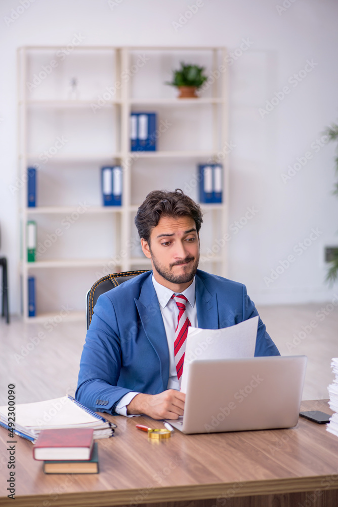 Young male employee and too much work in the office Young male employee and too much work in the office