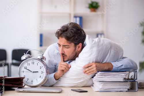 Foto Young male employee in oversleeping concept