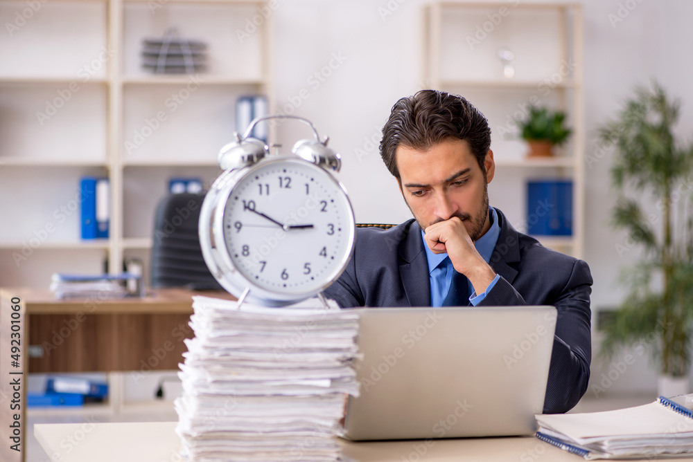 Young male employee in time management concept Young male employee in time management concept