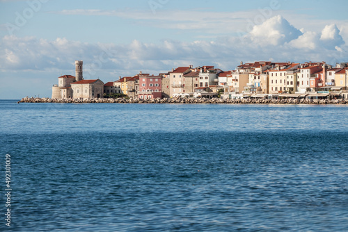 Panorama of Piran, Slovenia, with the Adriatic sea in front, with blue water and sky, on wharf quay, during a sunny summer afternoon. Piran, or Pirano, is slovenian city on the adriatic sea in istria