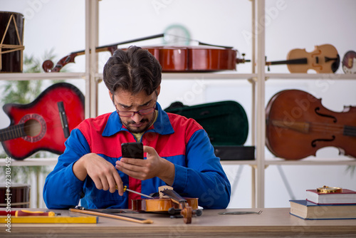 Fotografie Young man repairing musical instruments at workshop