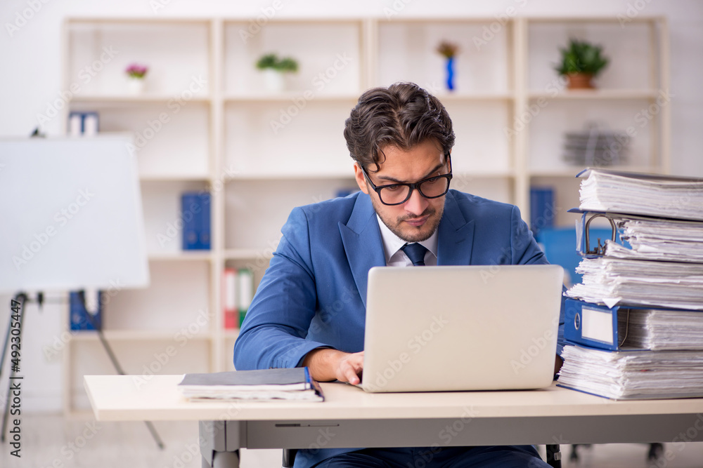 Young male employee and too much work in the office Young male employee and too much work in the office