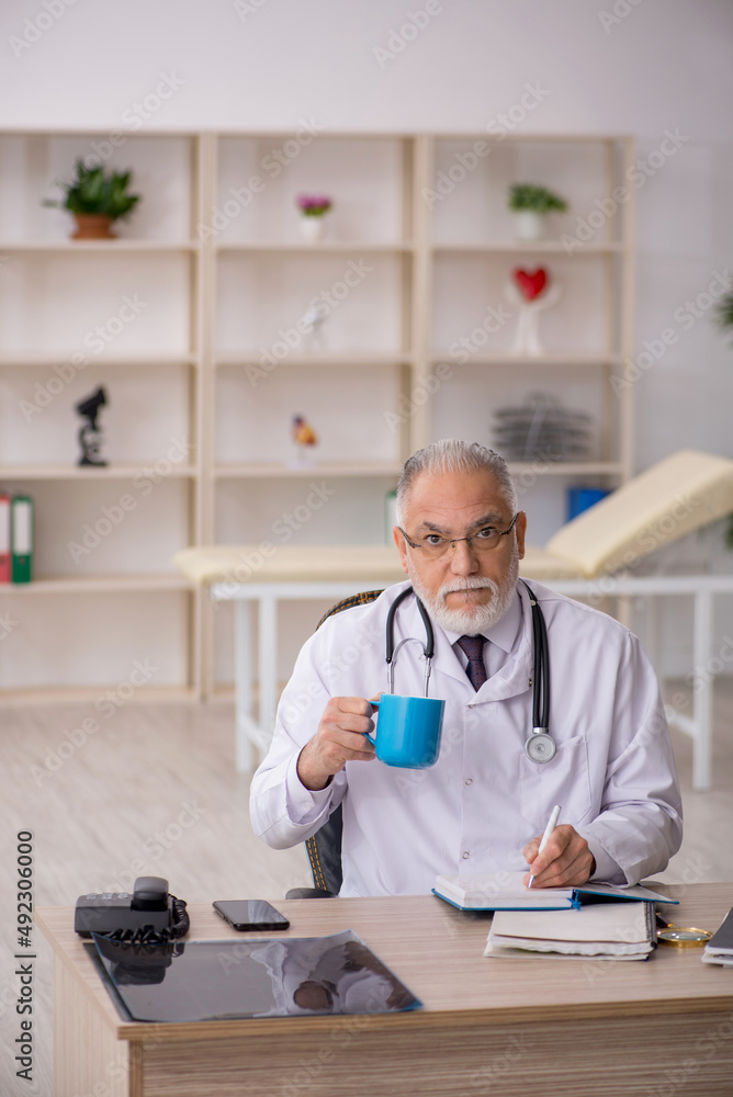 Old male doctor working in the clinic Old male doctor working in the clinic