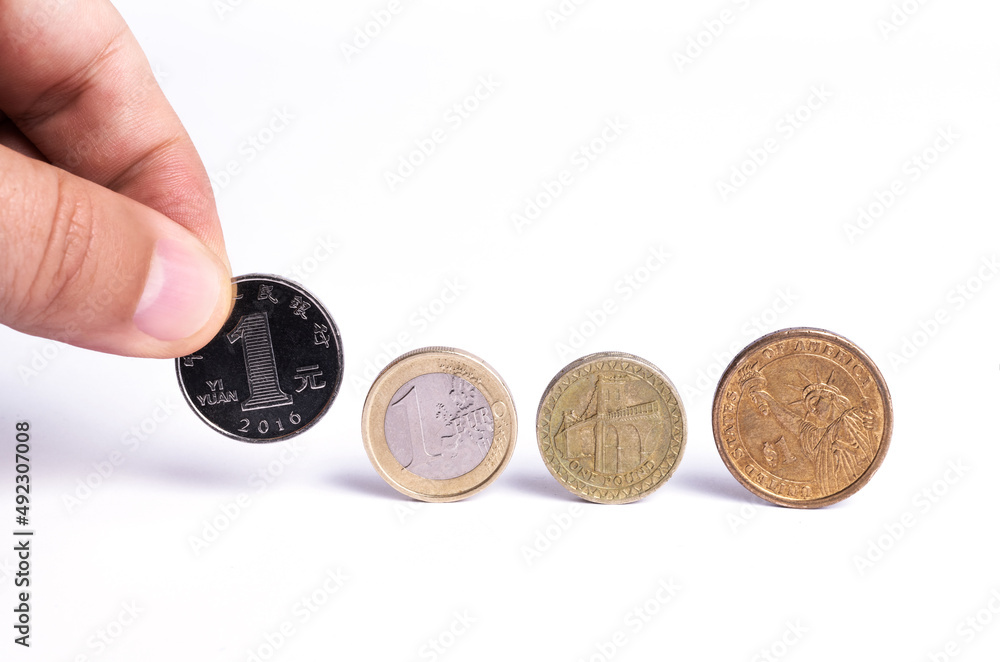 Fototapeta premium Coins on the edge of one yuan, one euro, one pound, one dollar on a white background. A composition symbolizing the importance of the leading currencies in the global economic arena.