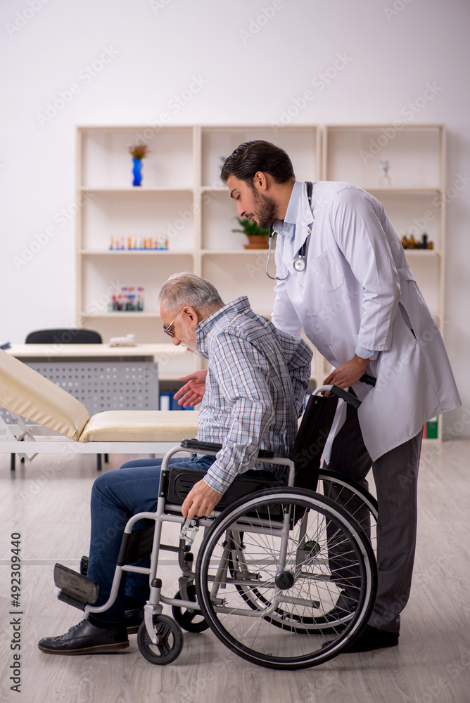Old man in wheelchair visiting young male doctor Old man in wheelchair visiting young male doctor