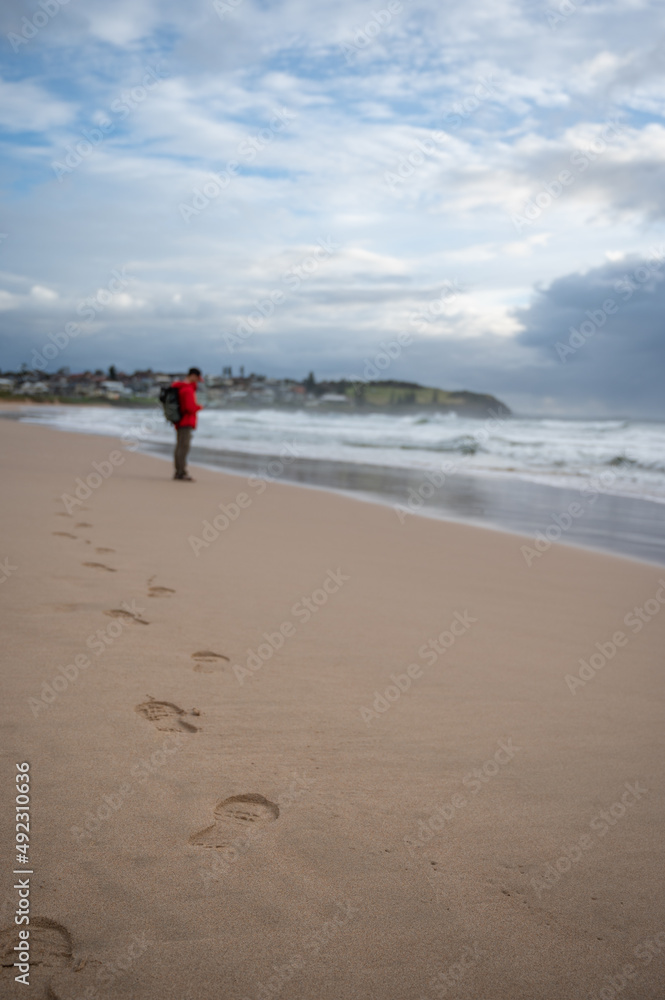 footprints on the sand and unrecognizable man on the beach with blur background footprints on the sand and unrecognizable man on the beach with blur background