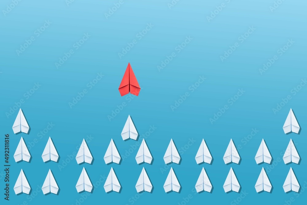 Business for new ideas creativity, innovative and solution concepts. Group of white paper plane in one direction and one red paper plane pointing in different way on blue background. Business for new ideas creativity, innovative and solution concepts. Group of white paper plane in one direction and one red paper plane pointing in different way on blue background.