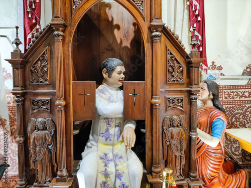 Photography GOA, INDIA - 13 Jan 2022 Statue of priest sitting behind the grid and listening the confession in the church