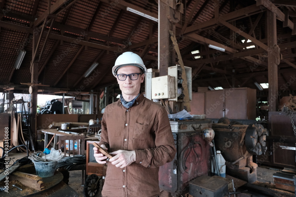 Worker in a construction helmet in a warehouse or workshop Worker in a construction helmet in a warehouse or workshop