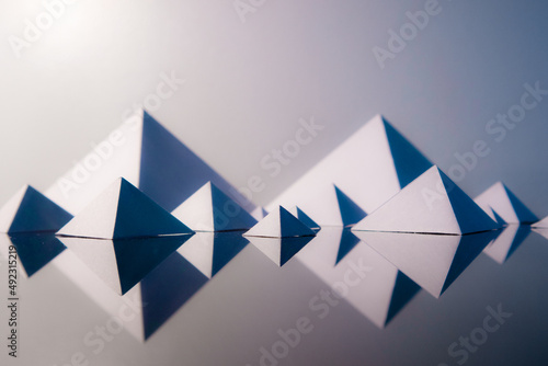 White origami pyramids on reflective glass