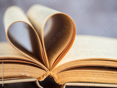 The heart shape created by the open yellowed pages of an old hardcover book, soft focus, shallow depth of field. I love reading! Educational topics. No people