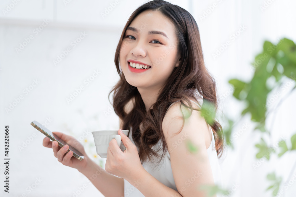 Young Asian woman using smartphone at home in the morning Young Asian woman using smartphone at home in the morning