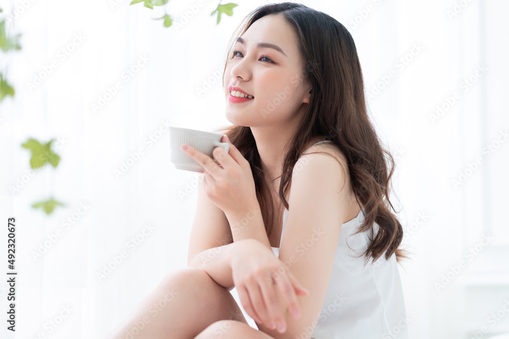 Image of beautiful young Asian woman drinking tea at home in the morning Image of beautiful young Asian woman drinking tea at home in the morning