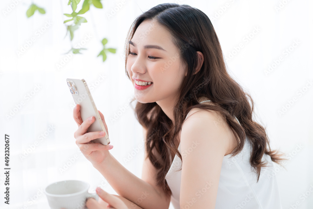 Young Asian woman using smartphone at home in the morning Young Asian woman using smartphone at home in the morning