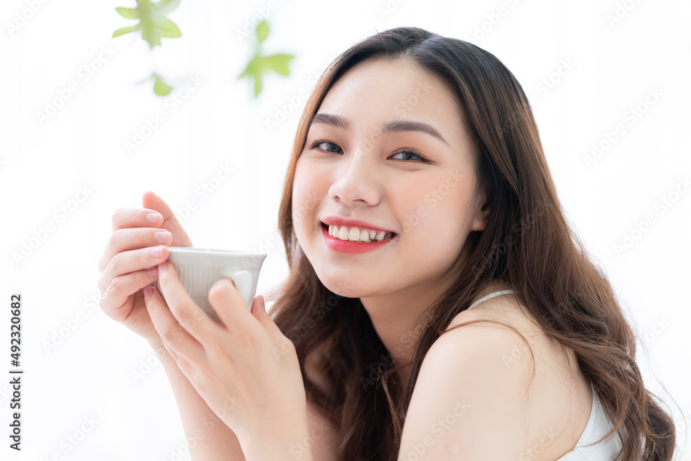 Image of beautiful young Asian woman drinking tea at home in the morning Image of beautiful young Asian woman drinking tea at home in the morning