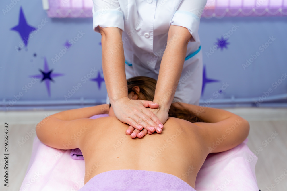 Fototapeta premium Top view of hands massaging female abdomen.Therapist applying pressure on belly. Woman receiving massage at spa salon