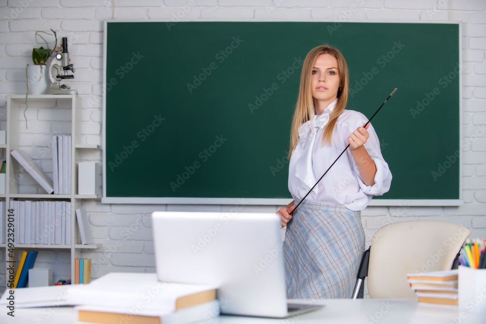Young teacher with pointer on blackboard with copy space. Portrait of a young, confident and attractive female student studying in school classroom. Young teacher with pointer on blackboard with copy space. Portrait of a young, confident and attractive female student studying in school classroom.