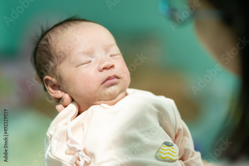 The newborn was held on her mother's arm with a hand around her neck while she slept.