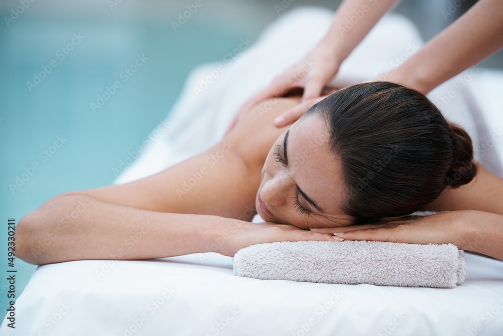 Losing herself in sublime comfort. Shot of a woman enjoying a massage beside a pool. Losing herself in sublime comfort. Shot of a woman enjoying a massage beside a pool.
