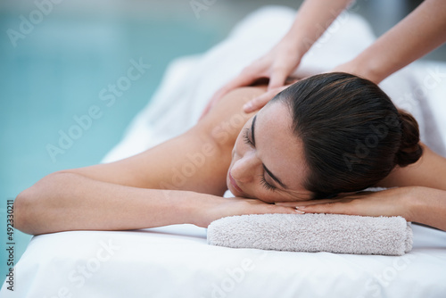 Losing herself in sublime comfort. Shot of a woman enjoying a massage beside a pool.