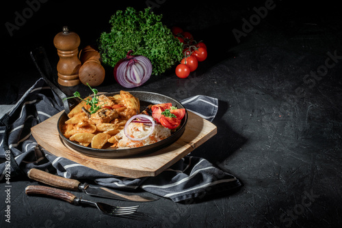 Roasted potato with cabbage stewed on frying pan in dark background