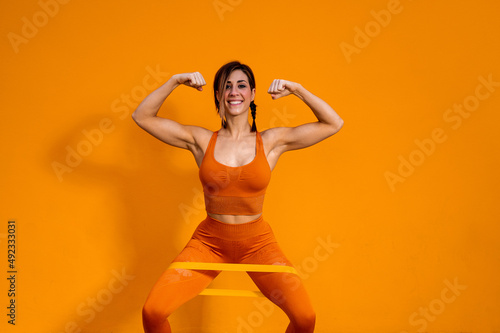 Alegre mujer deportista con unos auriculares haciendo ejercicios físicos sobre un fondo de color naranja photo