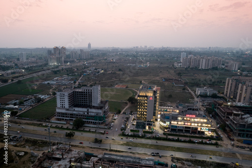 aerial dusk shot showing the 3 road shopping mall lit up with the under construction buildings around it unlit as the sun sets