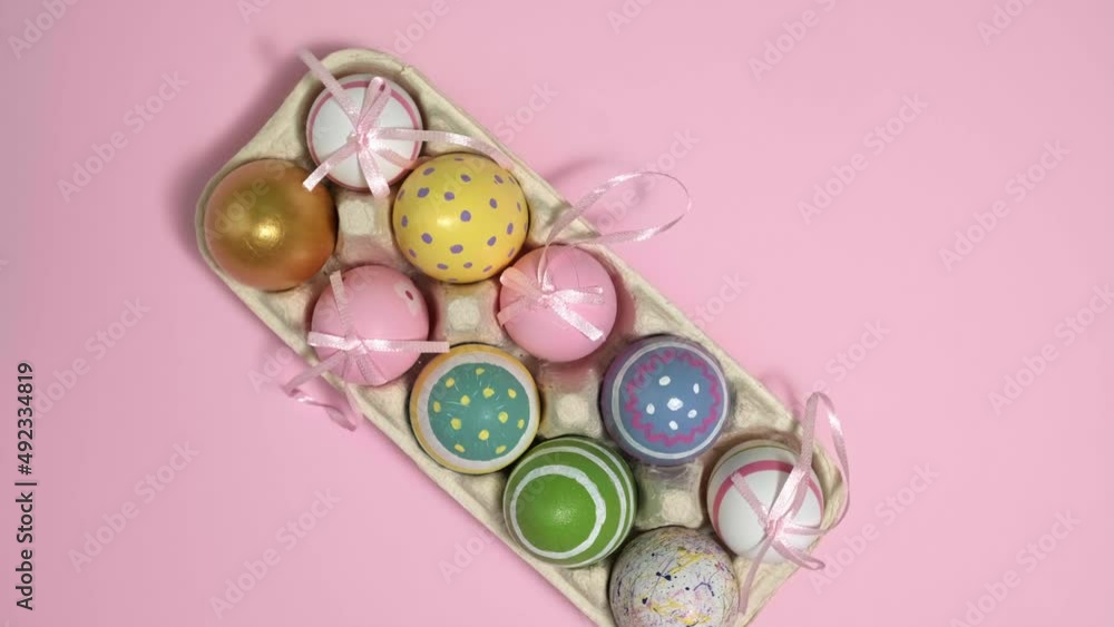4k. Rotating colorful Easter eggs In A Cardboard Box on pink background. Eggs In A Paper Egg Container. Multicolored egg for Happy easter. Hello spring and Happy Easter holiday concept. Top View 4k. Rotating colorful Easter eggs In A Cardboard Box on pink background. Eggs In A Paper Egg Container. Multicolored egg for Happy easter. Hello spring and Happy Easter holiday concept. Top View