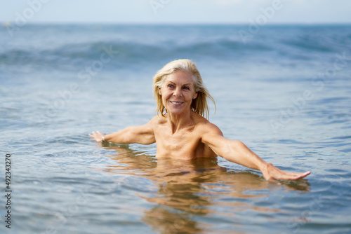 Eldery woman in good shape bathing in the sea. © javiindy