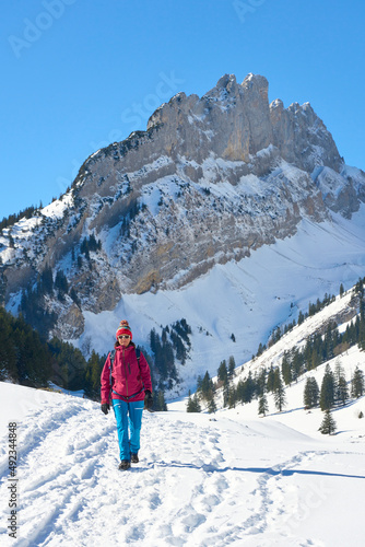 woman hiking in the snowy mountain landscape of the Alpstein mountain range near Appenzell, Switzerland