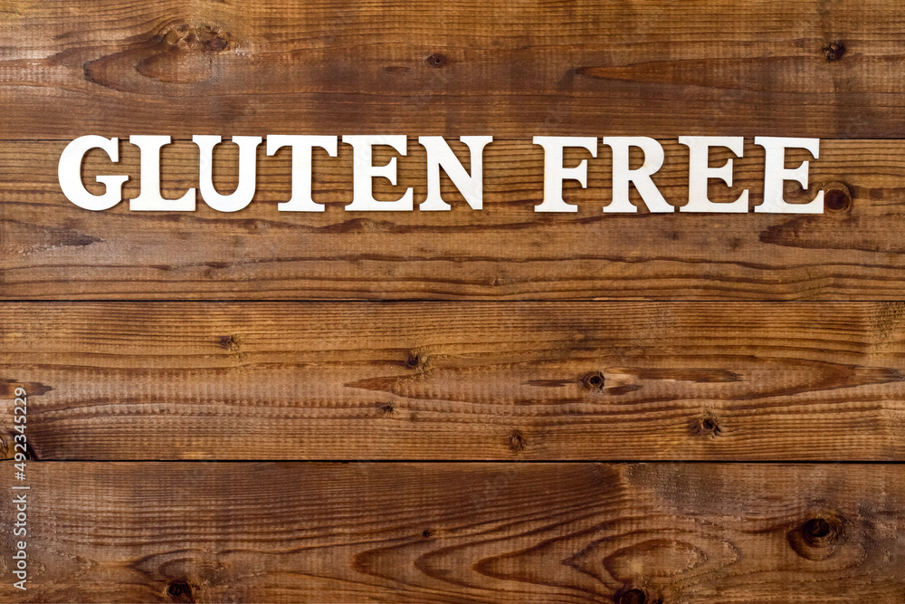 Gluten Free. Text in block letters on a wooden table. The concept of a gluten-free diet.Free space for design