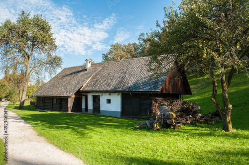 Old wooden houses in Slovenia in Europe. Summer weather, green grass with path leading around old cottages.