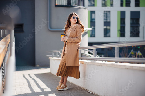 Young brunette woman in coat enjoys a cup of coffee