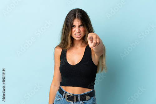 Young caucasian woman isolated on blue background frustrated and pointing to the front © luismolinero