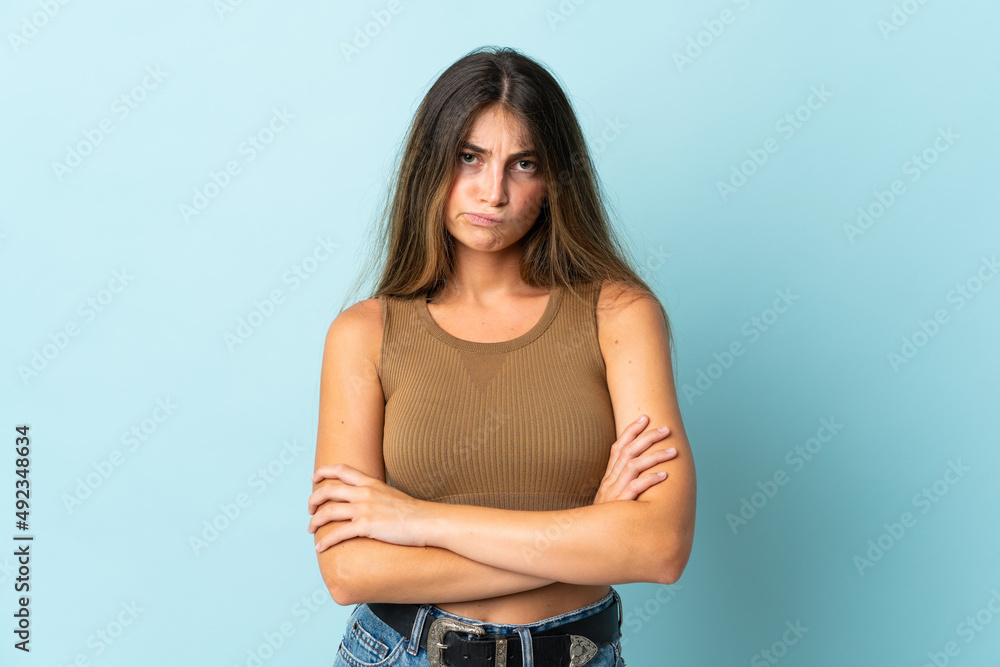 Obraz premium Young caucasian woman isolated on blue background with unhappy expression