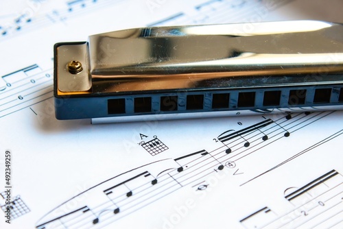 Closeup of a diatonic blues harmonica on a white page of sheet music