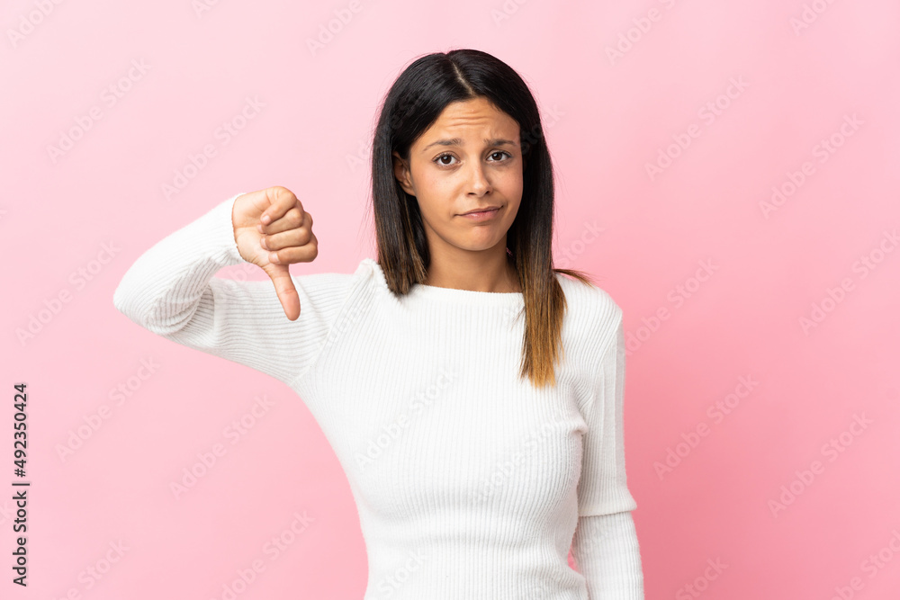 Caucasian girl isolated on pink background showing thumb down with negative expression Caucasian girl isolated on pink background showing thumb down with negative expression