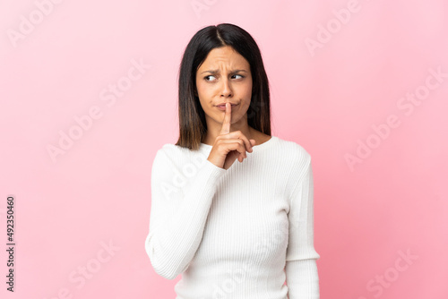 Caucasian girl isolated on pink background showing a sign of silence gesture putting finger in mouth