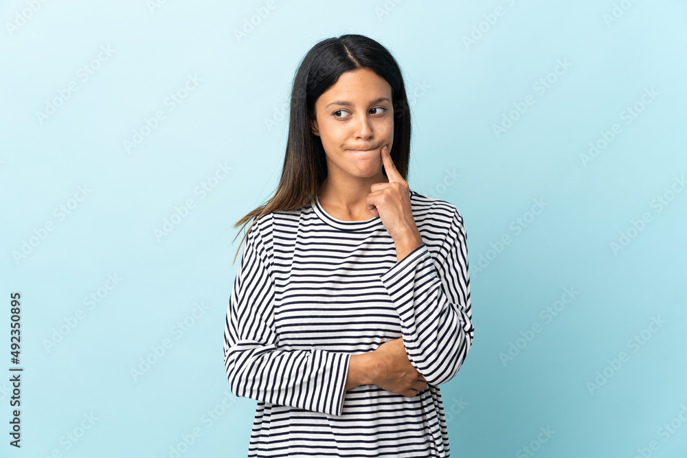 Caucasian girl isolated on blue background having doubts and thinking Caucasian girl isolated on blue background having doubts and thinking