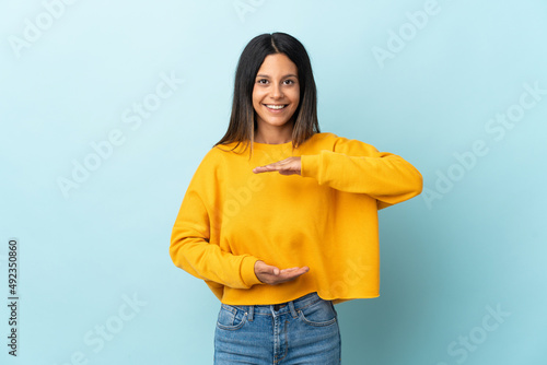 Caucasian girl isolated on blue background holding copyspace imaginary on the palm to insert an ad