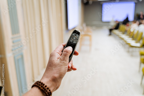 Press the button with your finger in the background of the auditorium. Clicker to enable the presentation of the business event, hand holds the switch black. photo