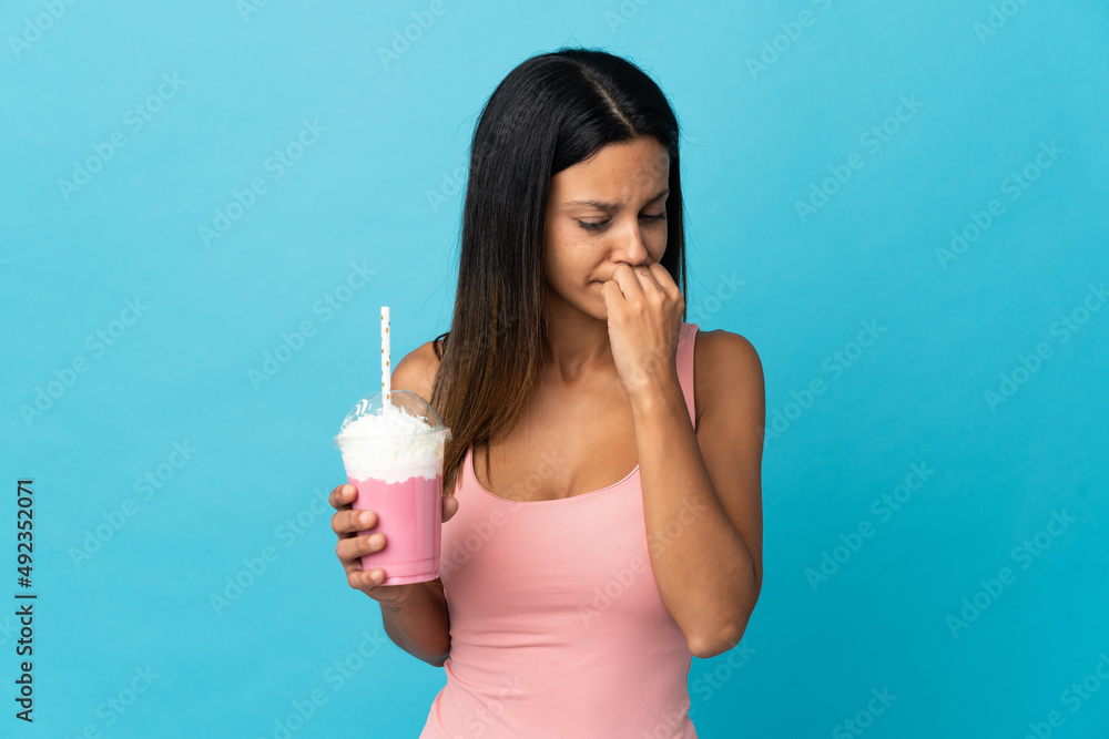 Young woman with strawberry milkshake having doubts Young woman with strawberry milkshake having doubts
