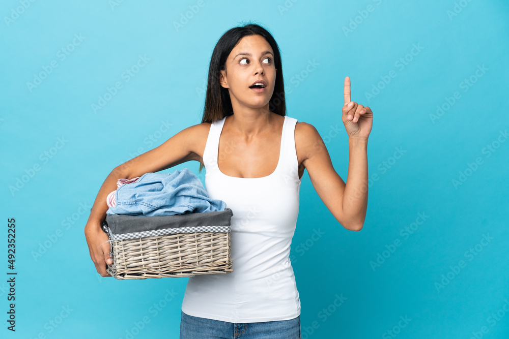 Young woman holding a clothes basket over isolated background thinking an idea pointing the finger up Young woman holding a clothes basket over isolated background thinking an idea pointing the finger up