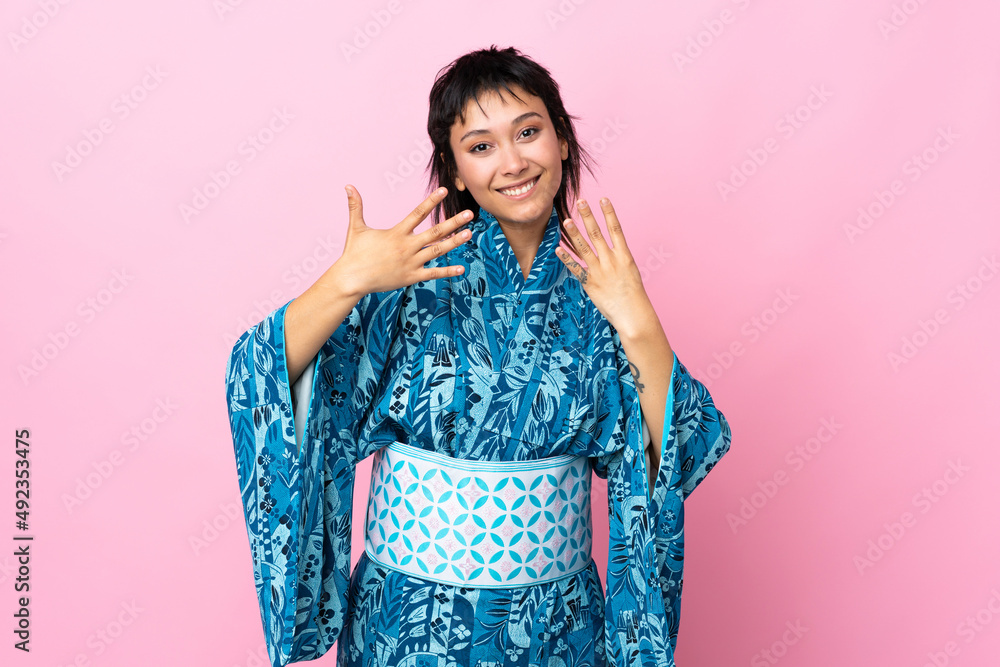 Young woman wearing kimono over isolated blue background counting nine with fingers Young woman wearing kimono over isolated blue background counting nine with fingers