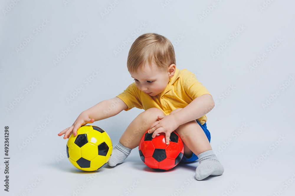Boy fan holding a soccer ball in his hands, isolated on a white background. newbie child in football, sport for kids. Little athlete. Yellow and blue football kit for kids Boy fan holding a soccer ball in his hands, isolated on a white background. newbie child in football, sport for kids. Little athlete. Yellow and blue football kit for kids