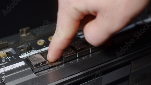 Close-up of a finger that presses the stop button on an old silver shiny cassette recorder