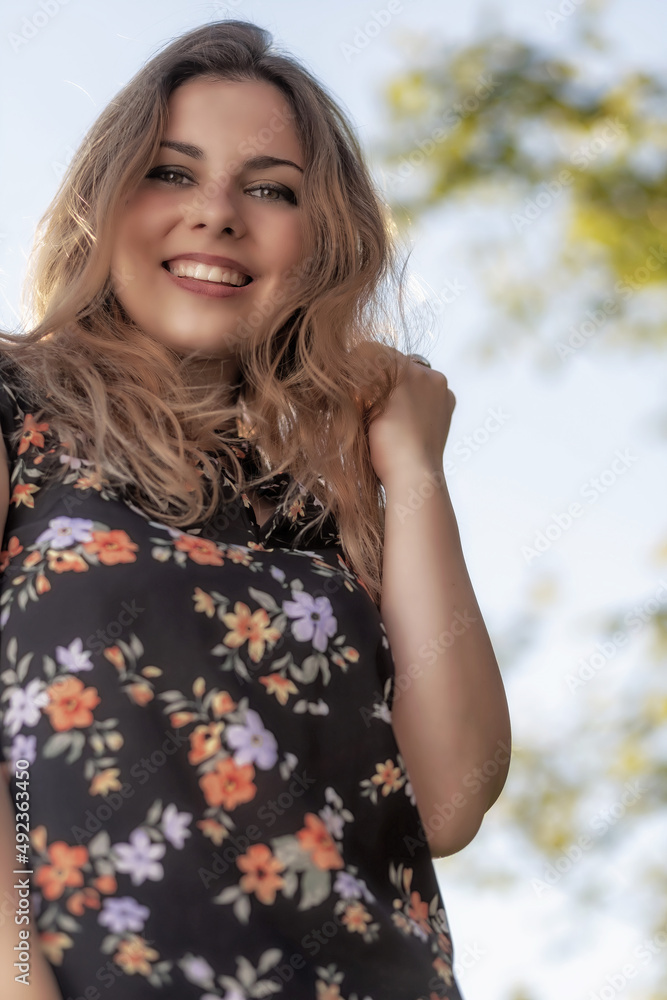 Portrait of attractive young woman standing outdoors against blue sky and smiling at the camera. Vertically. Portrait of attractive young woman standing outdoors against blue sky and smiling at the camera. Vertically.